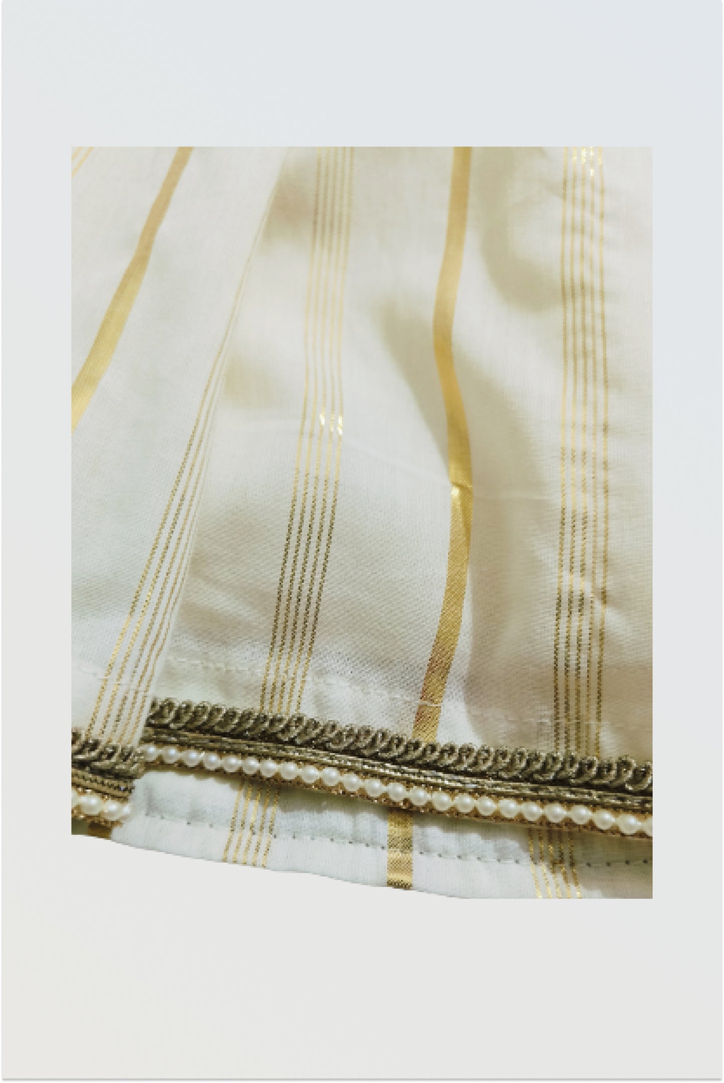 Close up of Kerala kasavu cotton fabric with golden lurex border and lace trim on skirt