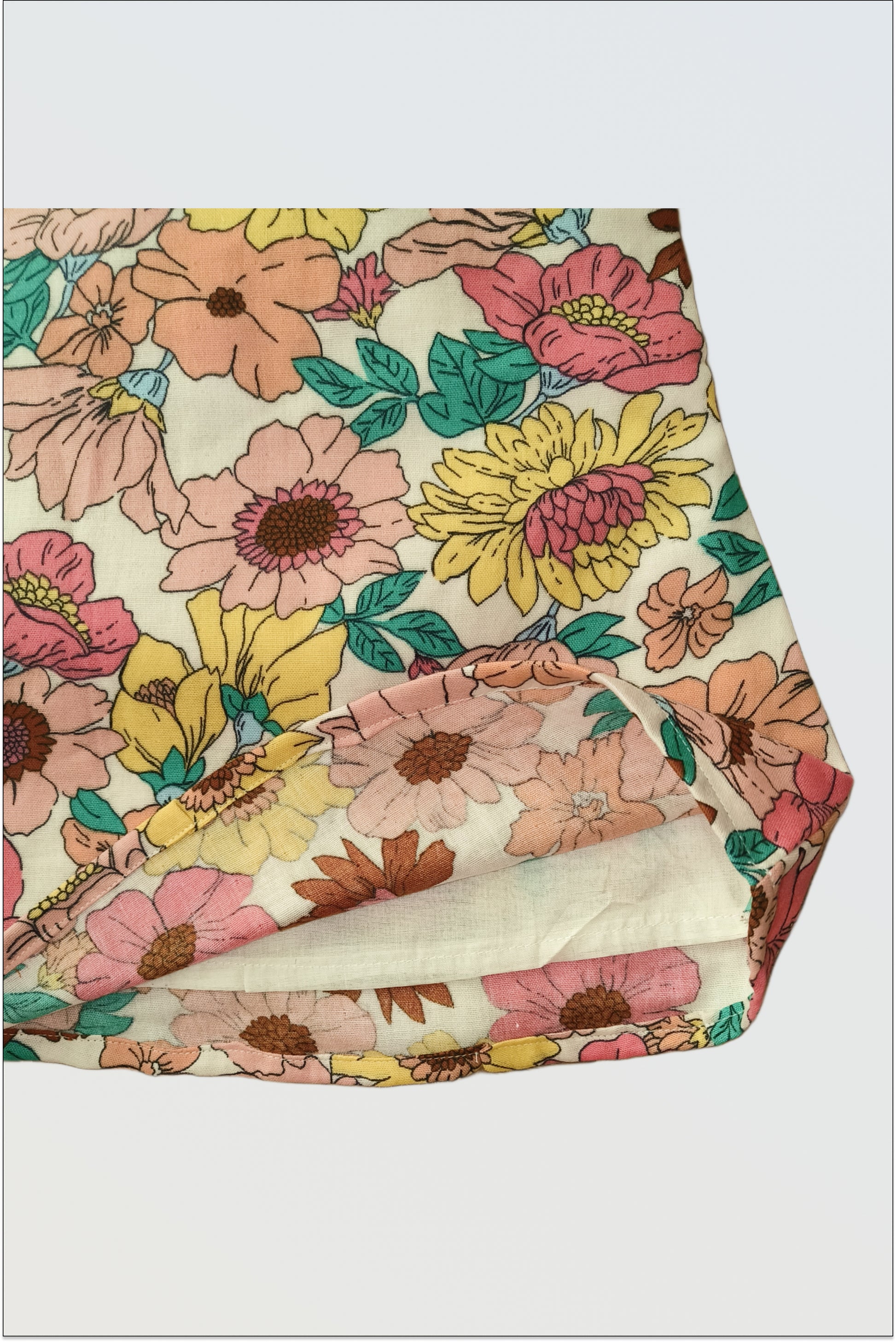 Detail of botanical floral print fabric on Summer Bloom dress showing pink yellow flowers and green leaves