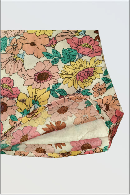 Detail of botanical floral print fabric on Summer Bloom dress showing pink yellow flowers and green leaves