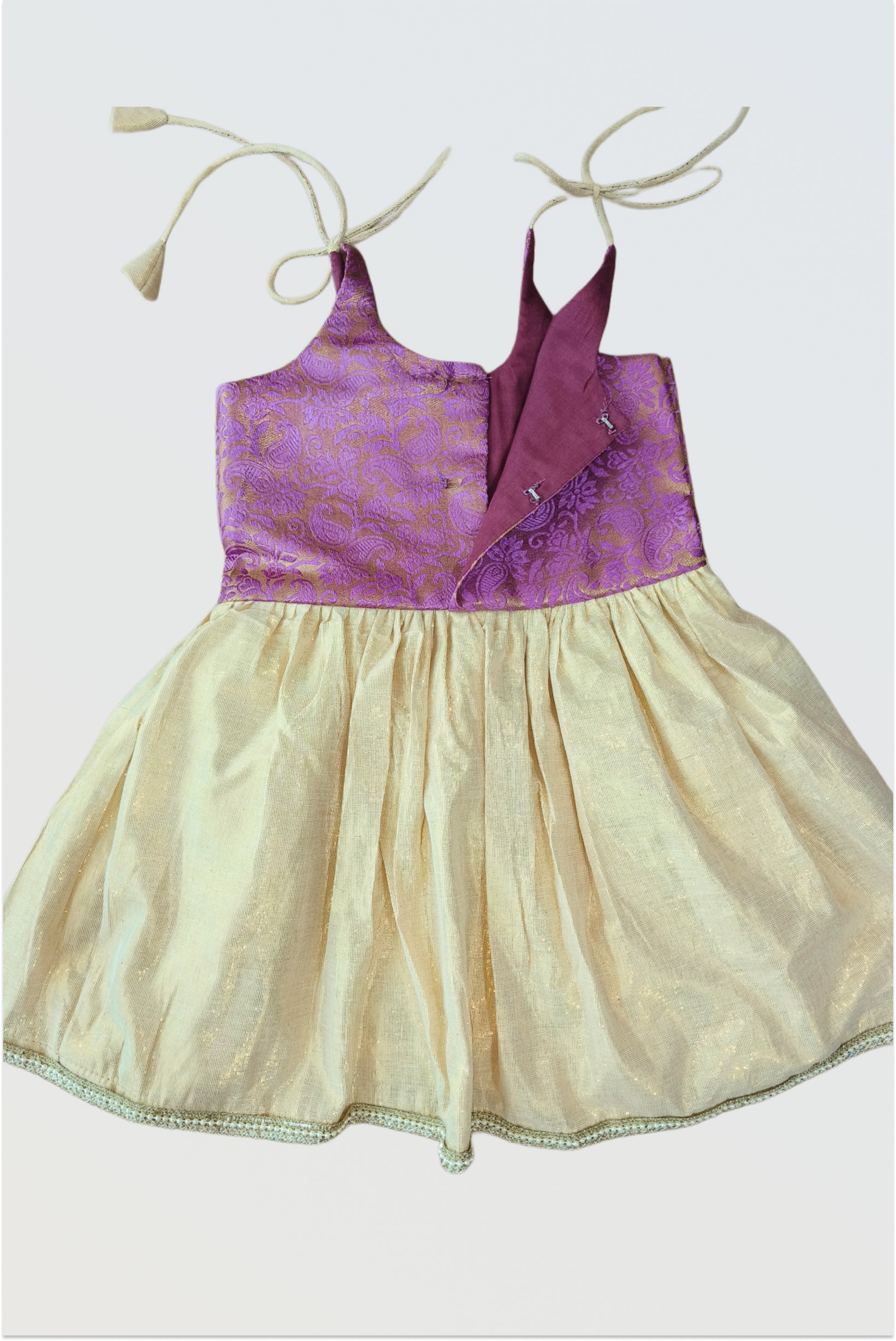 Back view of brocade tie-up frock showing adjustable shoulder straps and lace hem detail