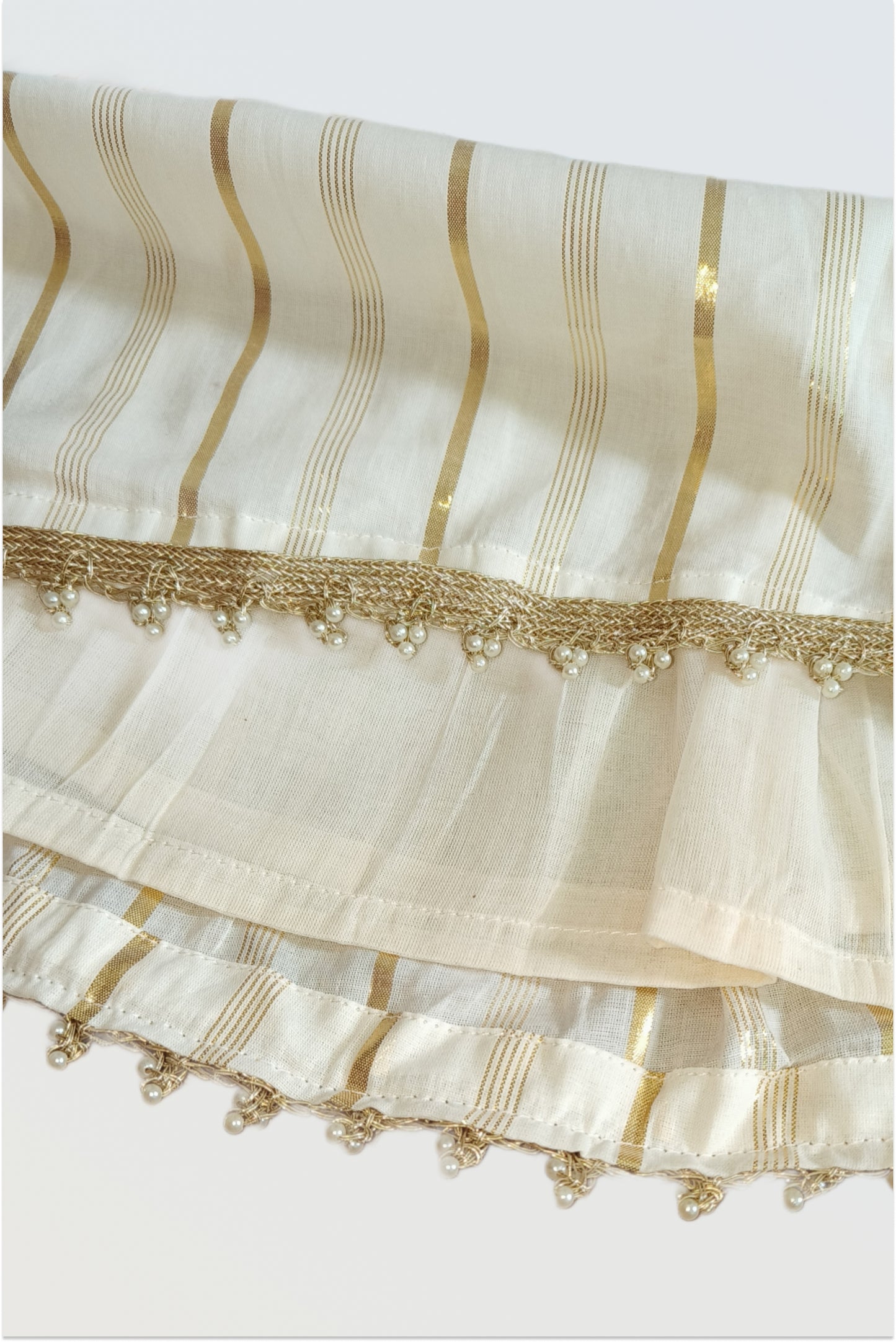 Close up of kasavu lehanga skirt showing golden lurex stripes and pearl lace trim detail