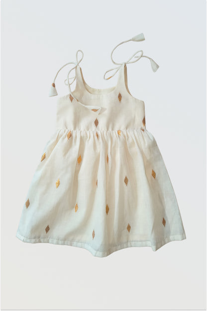 Baby wearing kasavu tie-up frock with golden lurex borders - traditional Kerala Onam dress