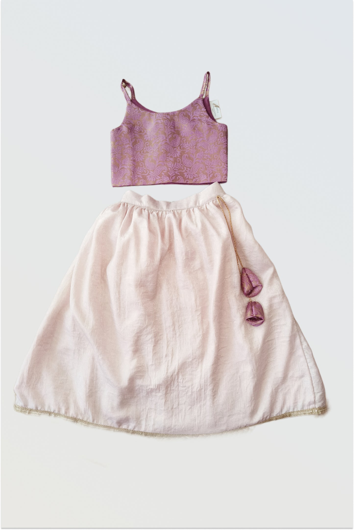 Pink brocade lehanga set flat lay showing lilac purple choli and soft blush pink skirt