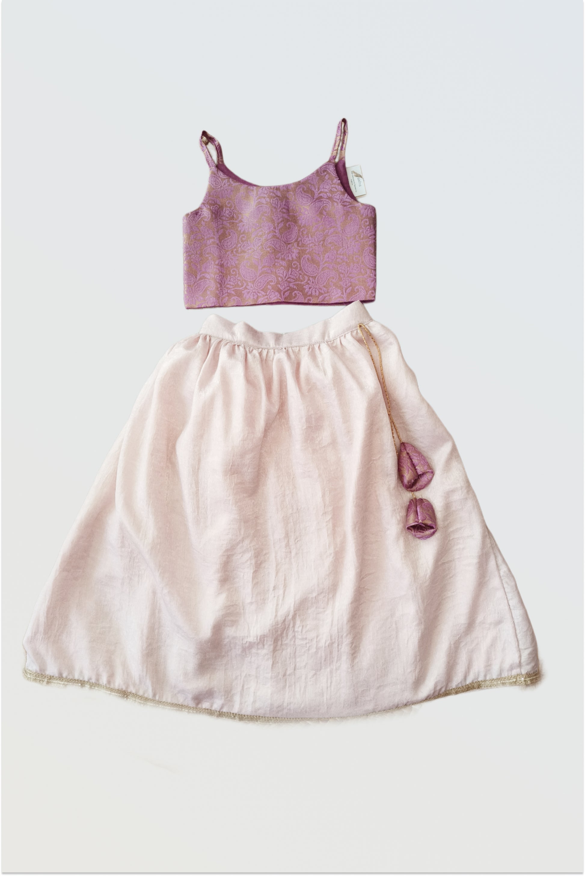 Pink brocade lehanga set flat lay showing lilac purple choli and soft blush pink skirt