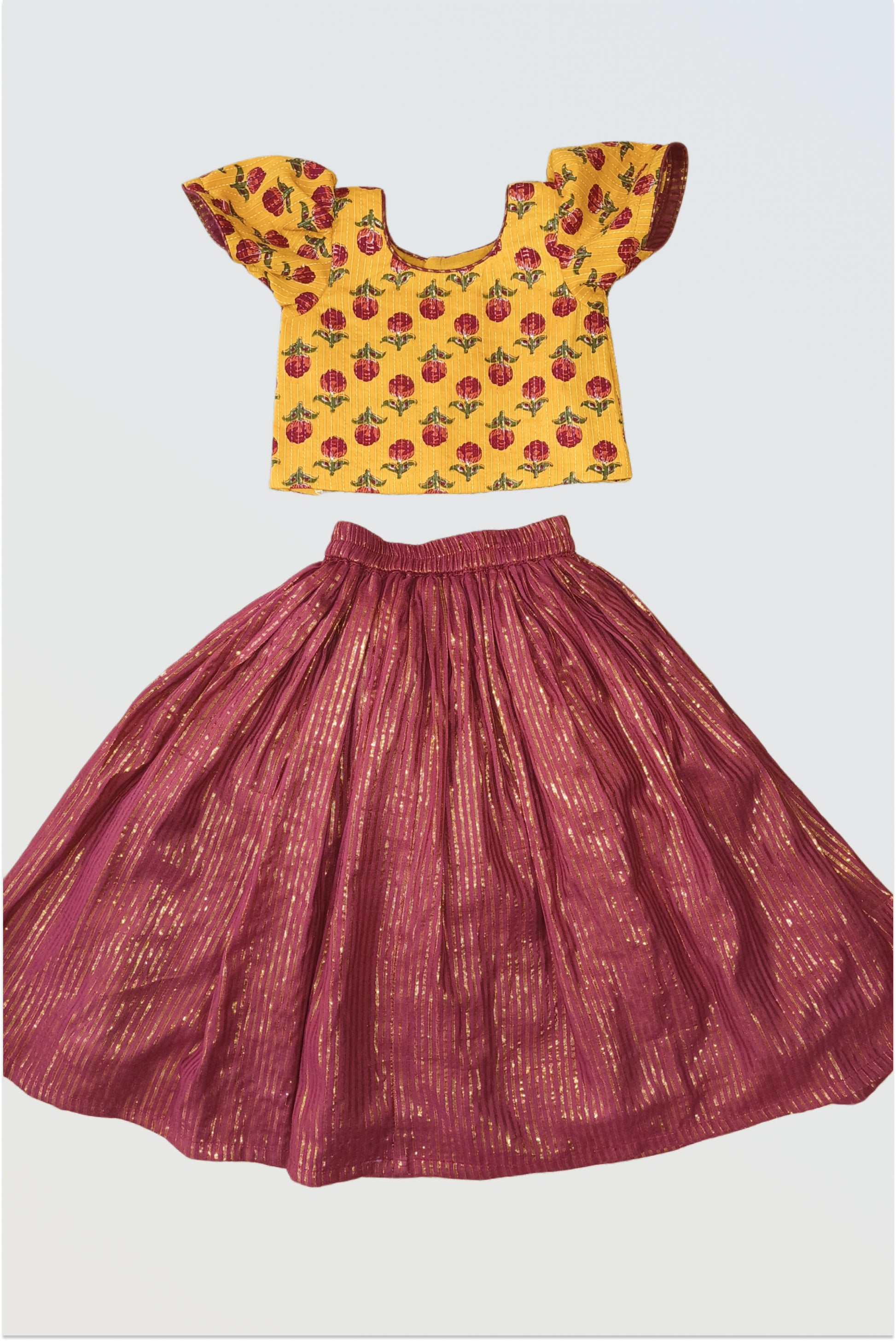 Yellow and maroon lehanga choli set flat lay showing block print top and maroon skirt