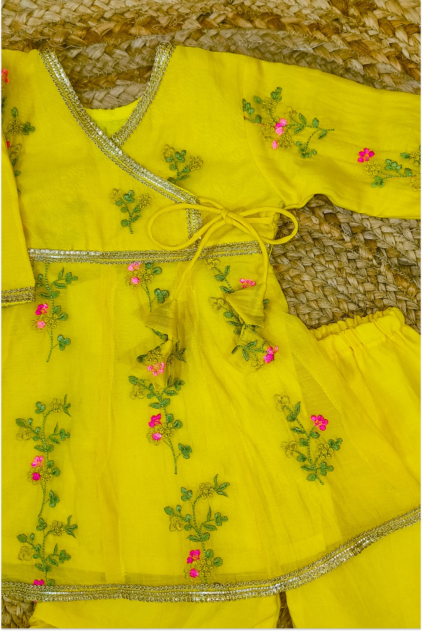 Yellow sharara pants with full flare showing hand embroidered floral design and golden lace hem detail